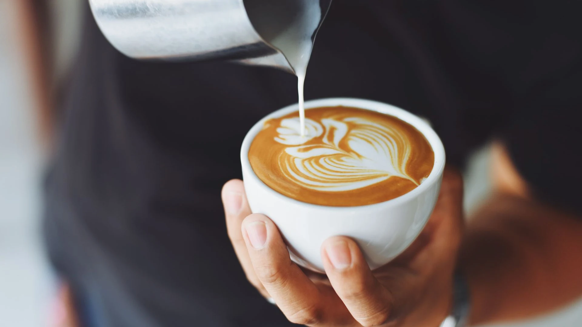 Barista pouring latte art into cup