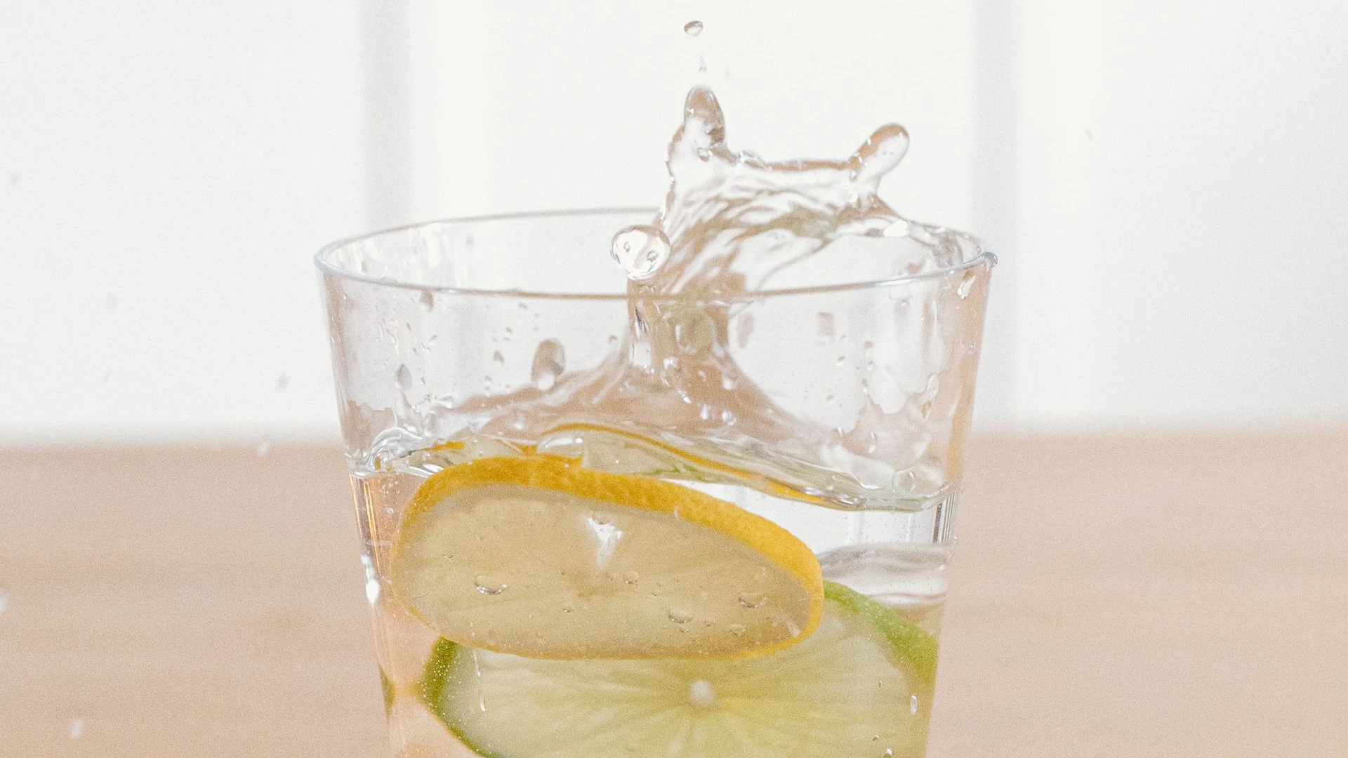 Lemon slice splashing into water glass