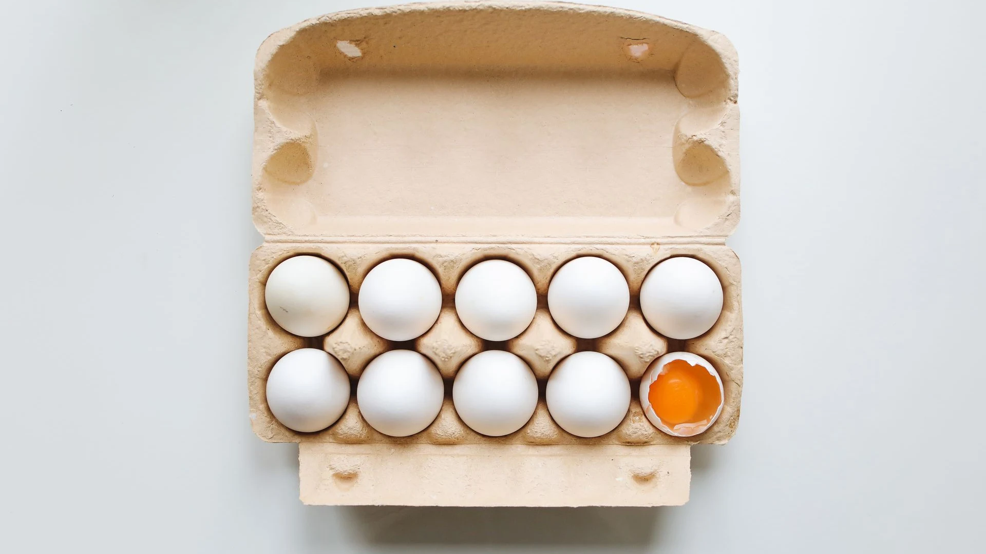 Open carton of identical white eggs