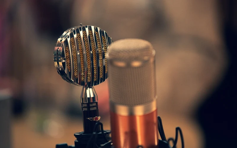 Two vintage microphones in warm studio light