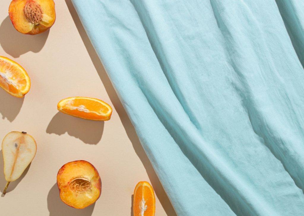 Stonefruit on a sandy background with a stretch of pale blue fabric. Picking the fright brand personality for your business can make the world of difference. 
